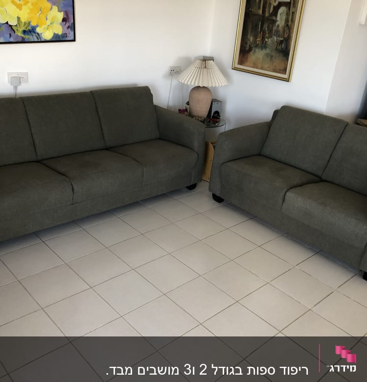 שתי ספות מרופדות בבד אפור כהה על רצפת אריחים לבנים